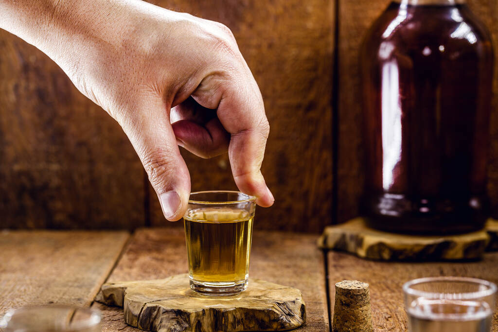 Homem pegando um copo de cachaça, como escolher cachaça